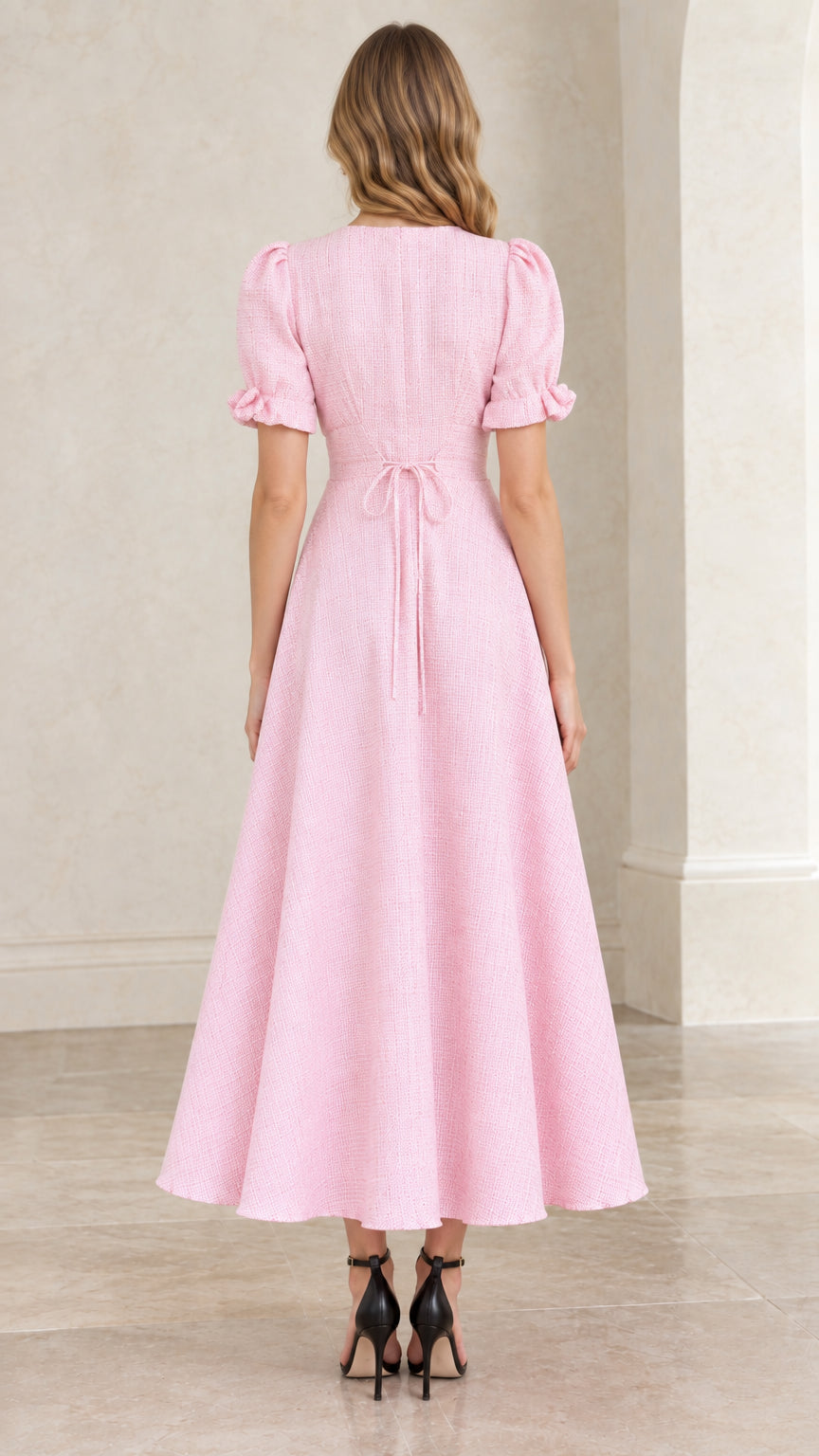 Back view of pastel pink textured dress highlighting tie back waist and zipper