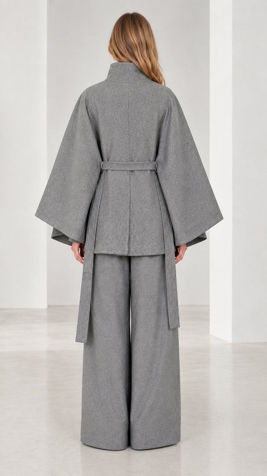 Back view of women's grey cape coat showing structured capelet back and tied belt