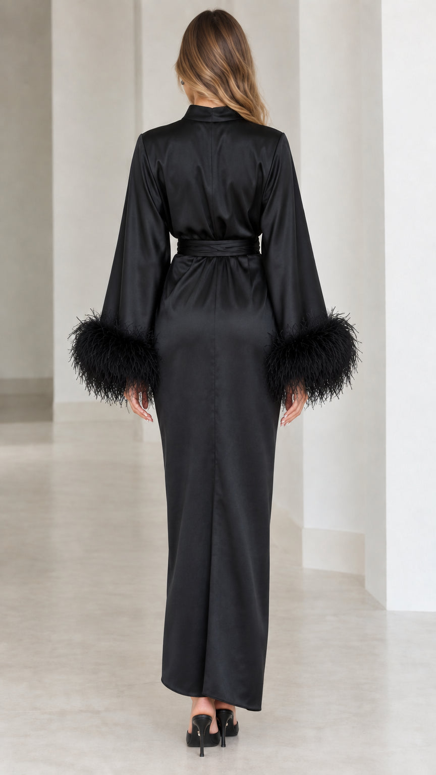 Back view of model wearing black satin mock neck gown with draped silhouette