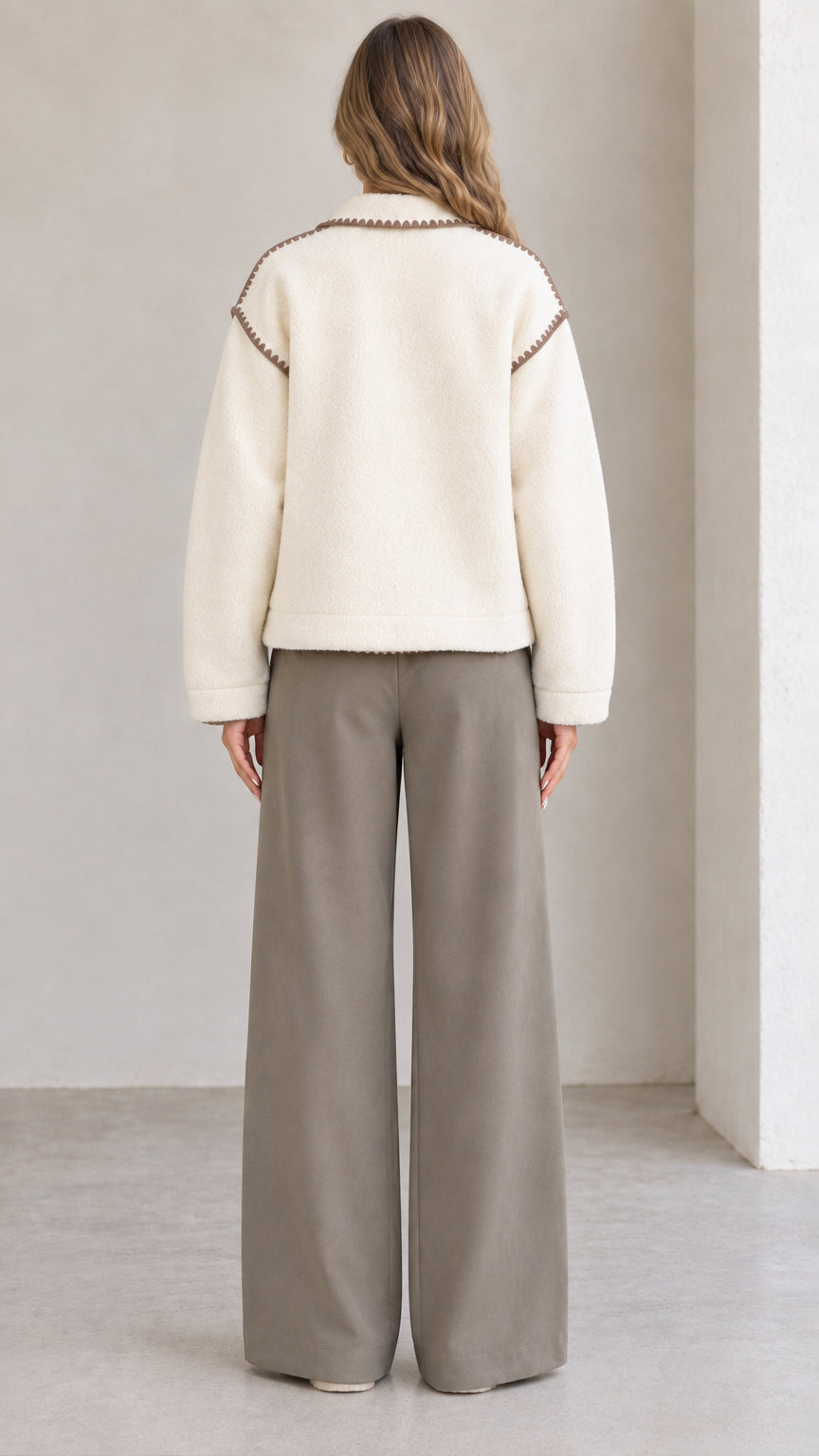 Back view of model wearing cream fleece jacket with decorative shoulder trim