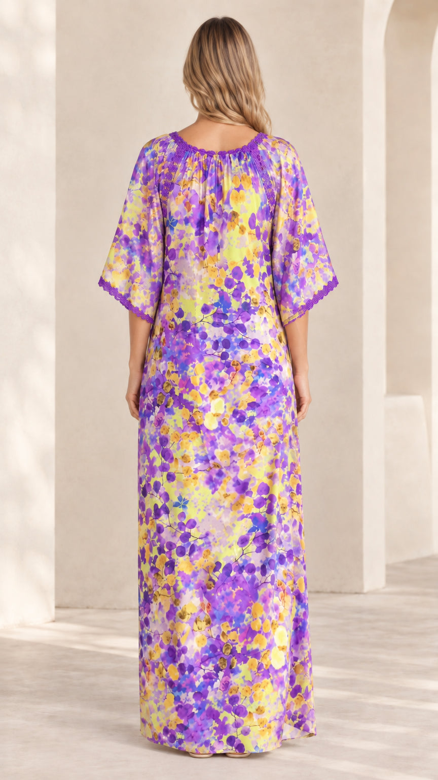 Back view of model in purple floral kaftan dress highlighting crochet neckline detail