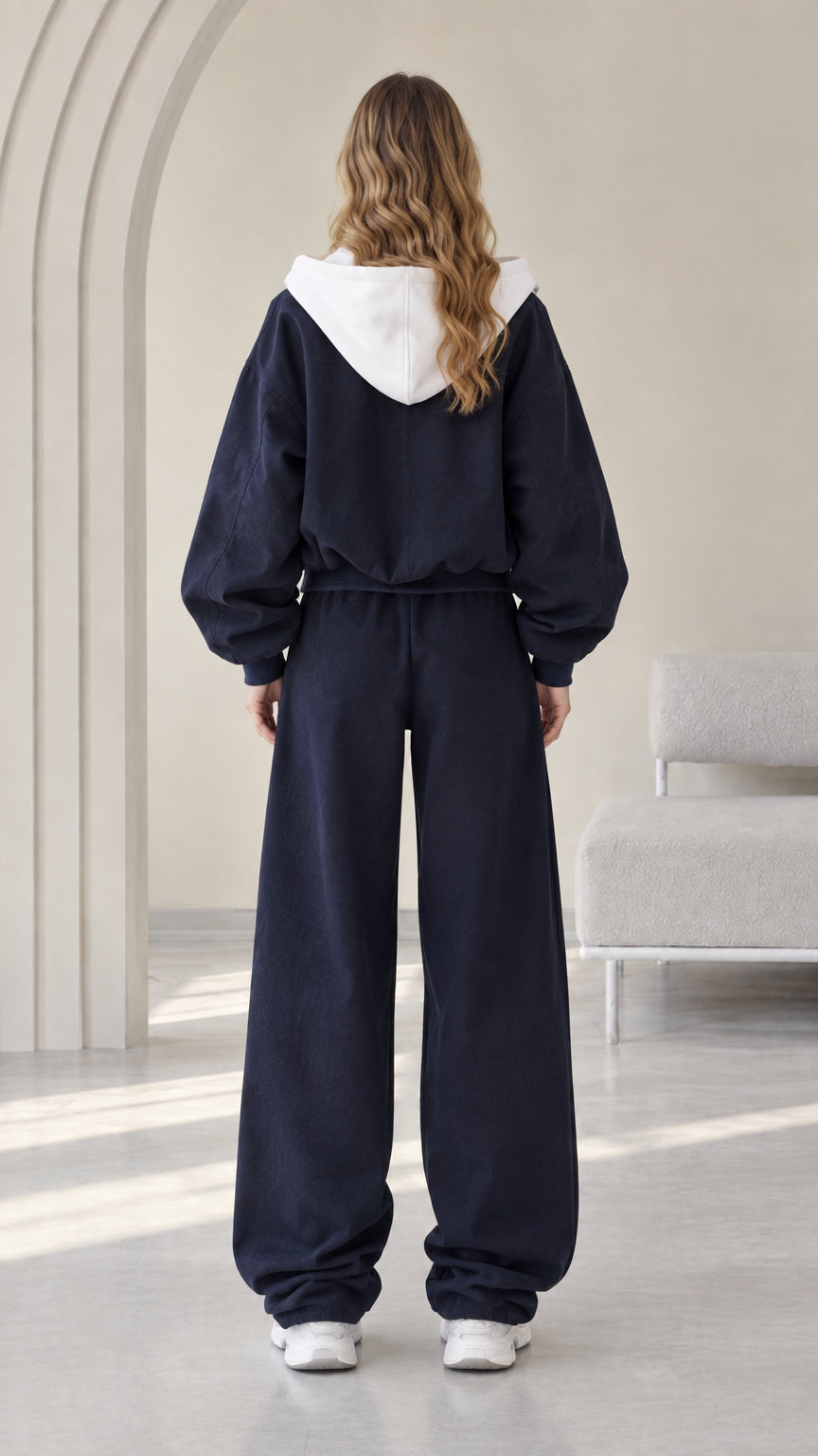 Back view of model showing the white contrast hood and relaxed pants fit in Navy Blue