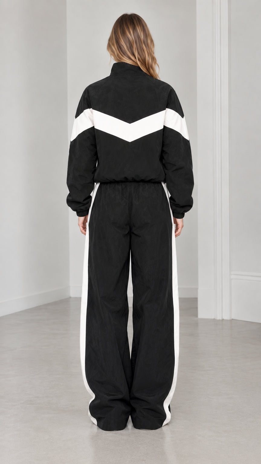 Back view of woman wearing black chevron colorblock tracksuit jacket and matching trousers
