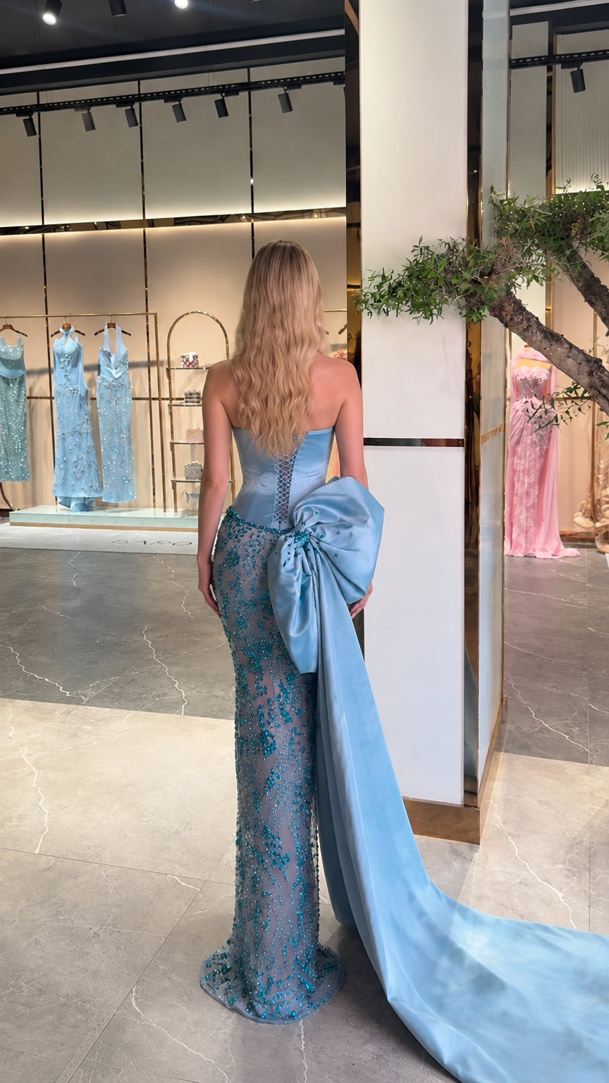 Back view of model in sky blue sweetheart evening gown with dramatic sweeping train