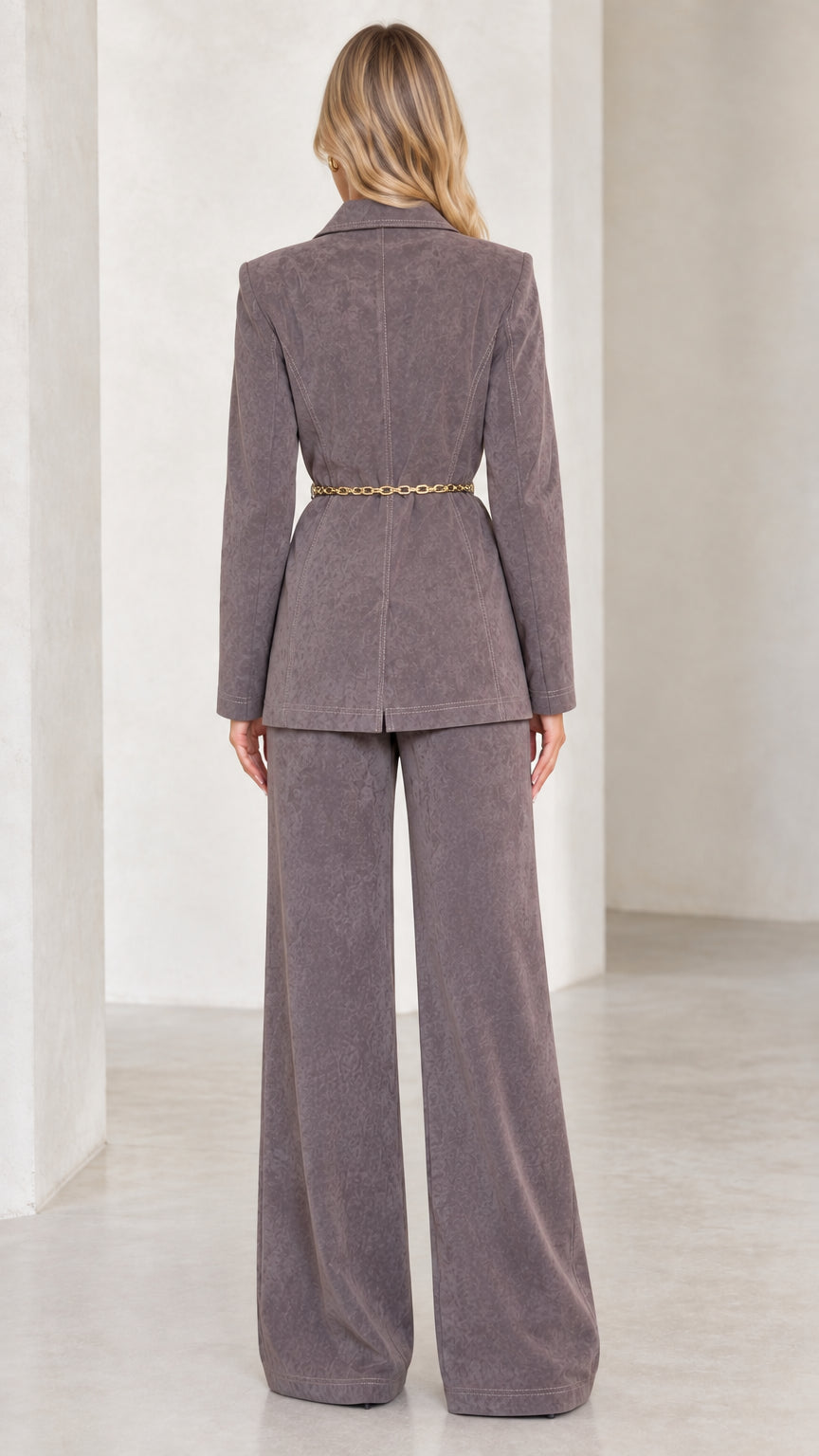 Back view of charcoal grey two-piece suit showing belted waist and clean trouser drape