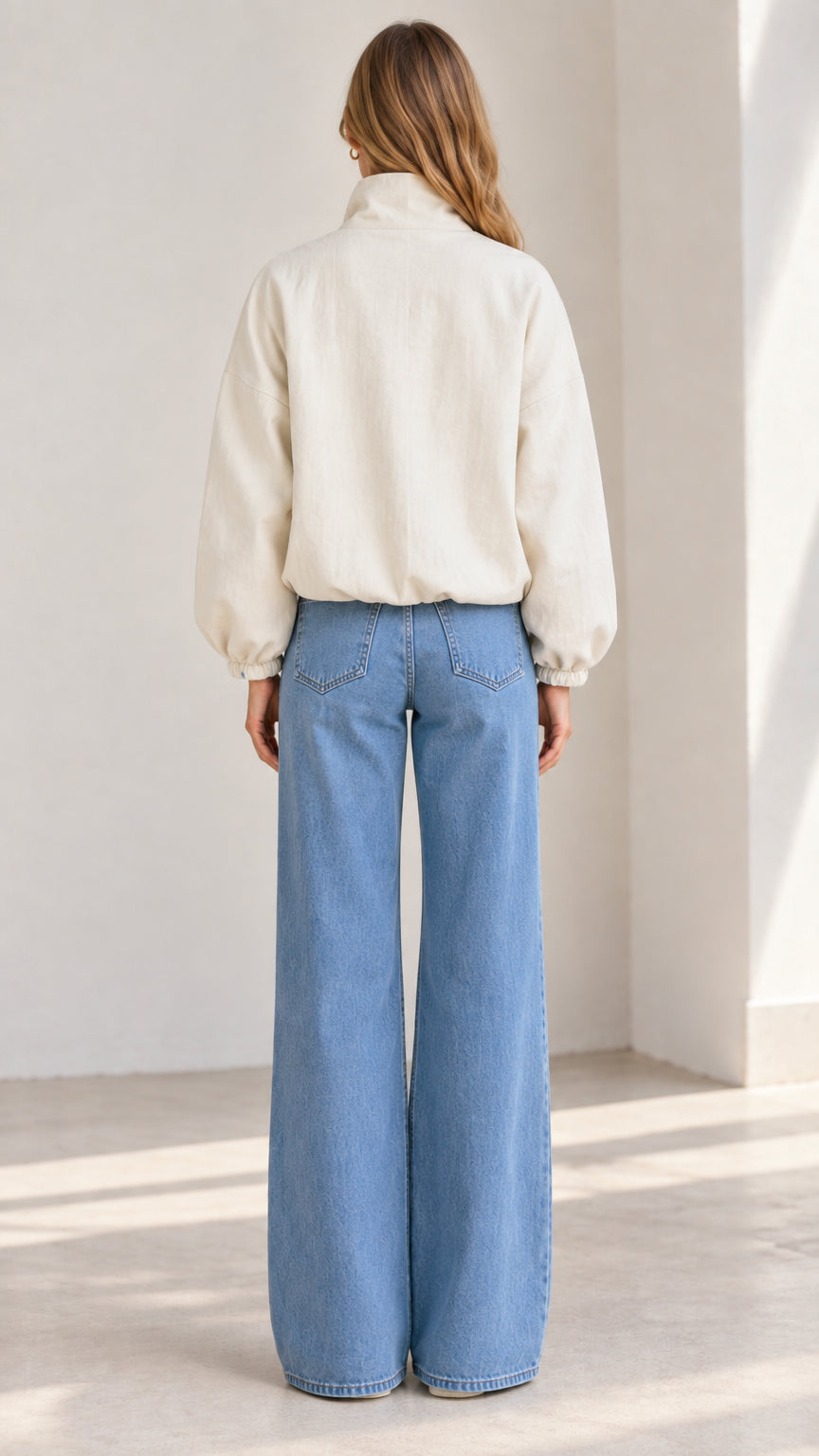 Back view of the woman wearing the relaxed beige waist-length bomber jacket