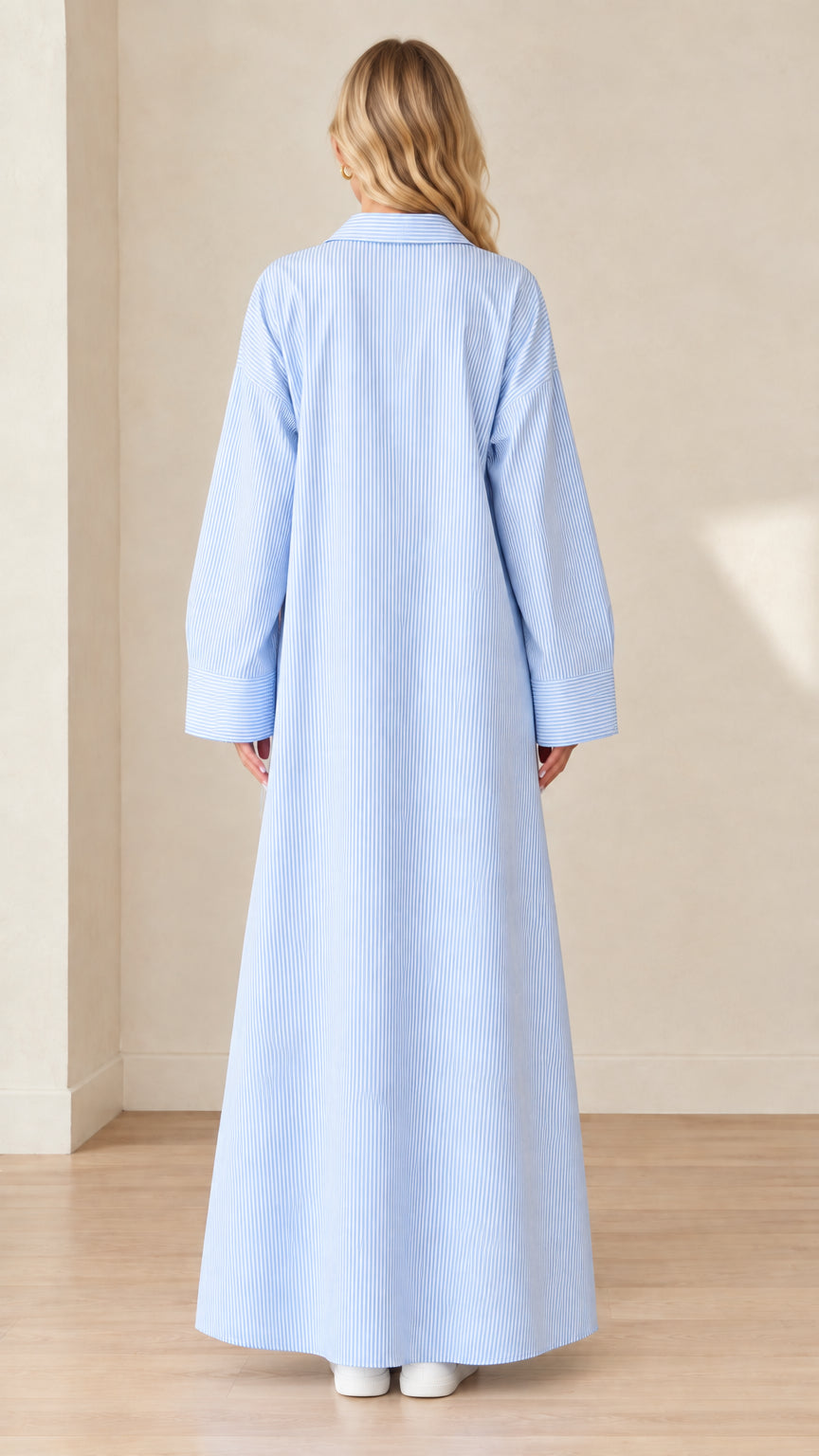 Back view of a model wearing a floor-length light blue striped shirt dress