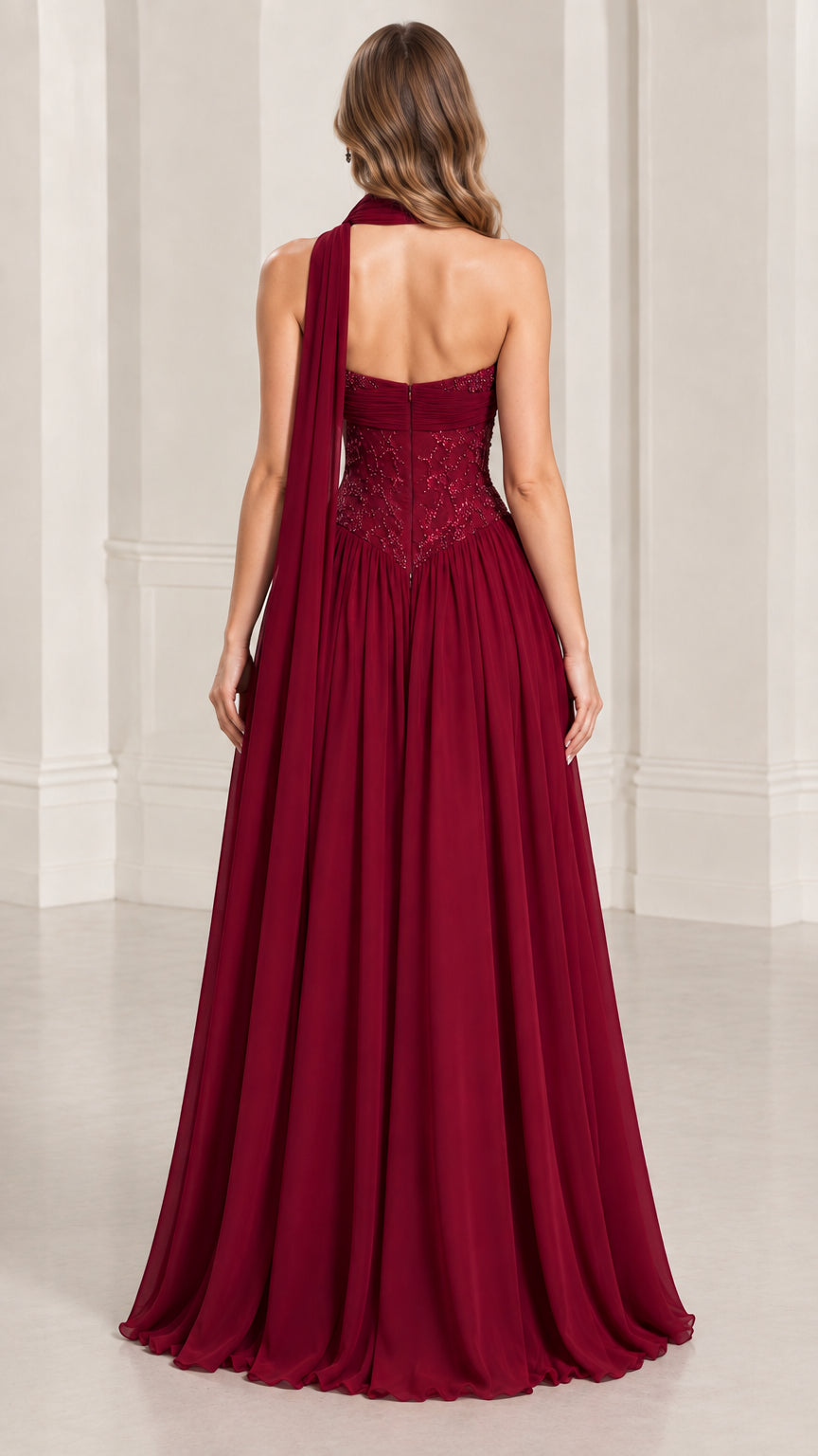 Back view of model showcasing flowing burgundy gown with back neck sash
