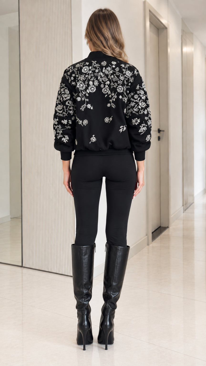 Back view of model showing detailed floral embroidery across back of black bomber jacket