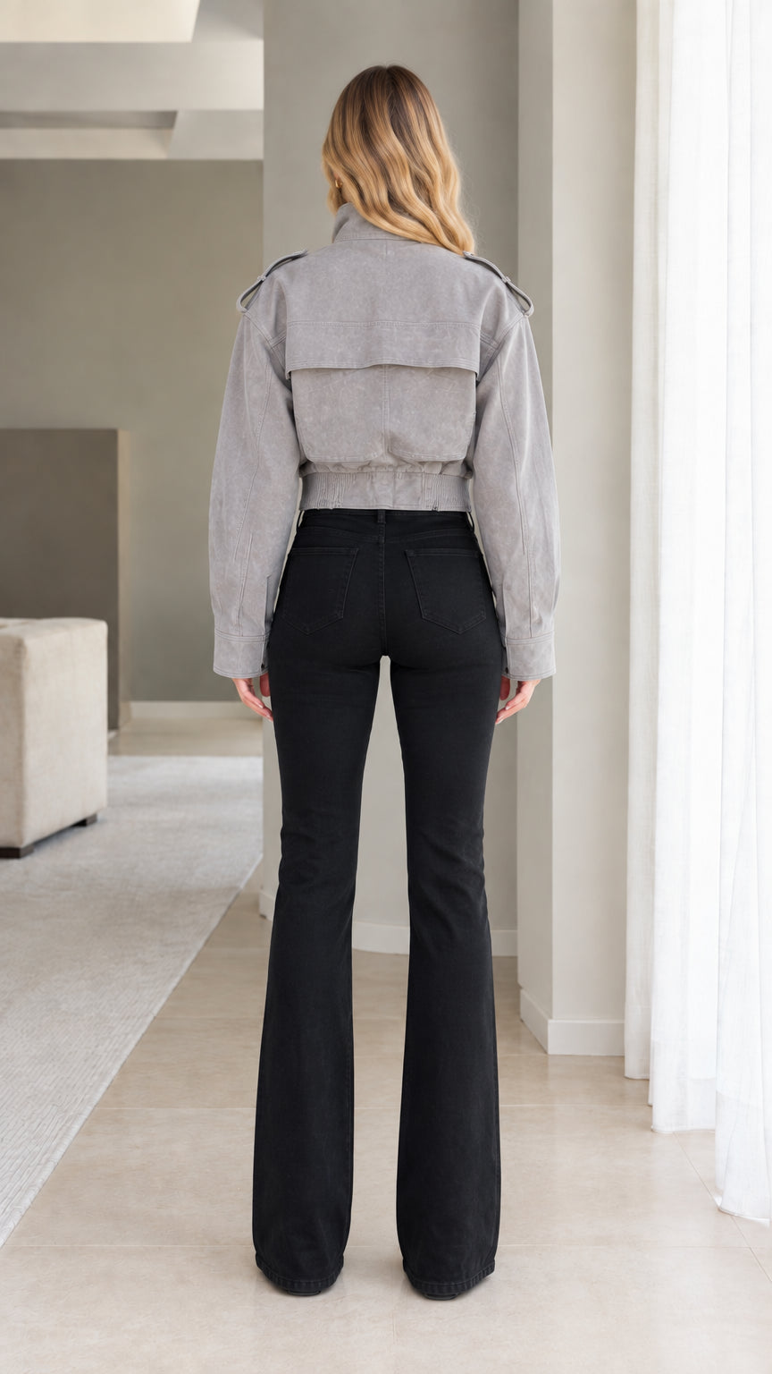 Model wearing Grey cropped utility jacket, back view showing back storm flap detail