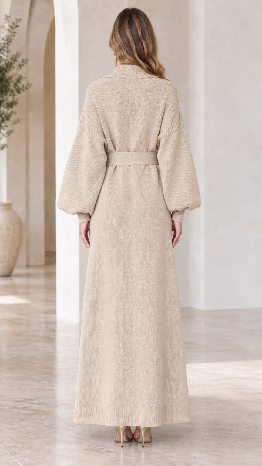 Back view of woman wearing floor-length beige belted knit cardigan