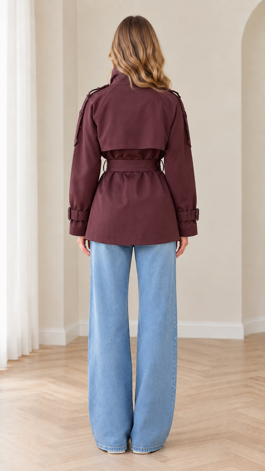 Back view of burgundy short trench coat showing storm flap and waist belt
