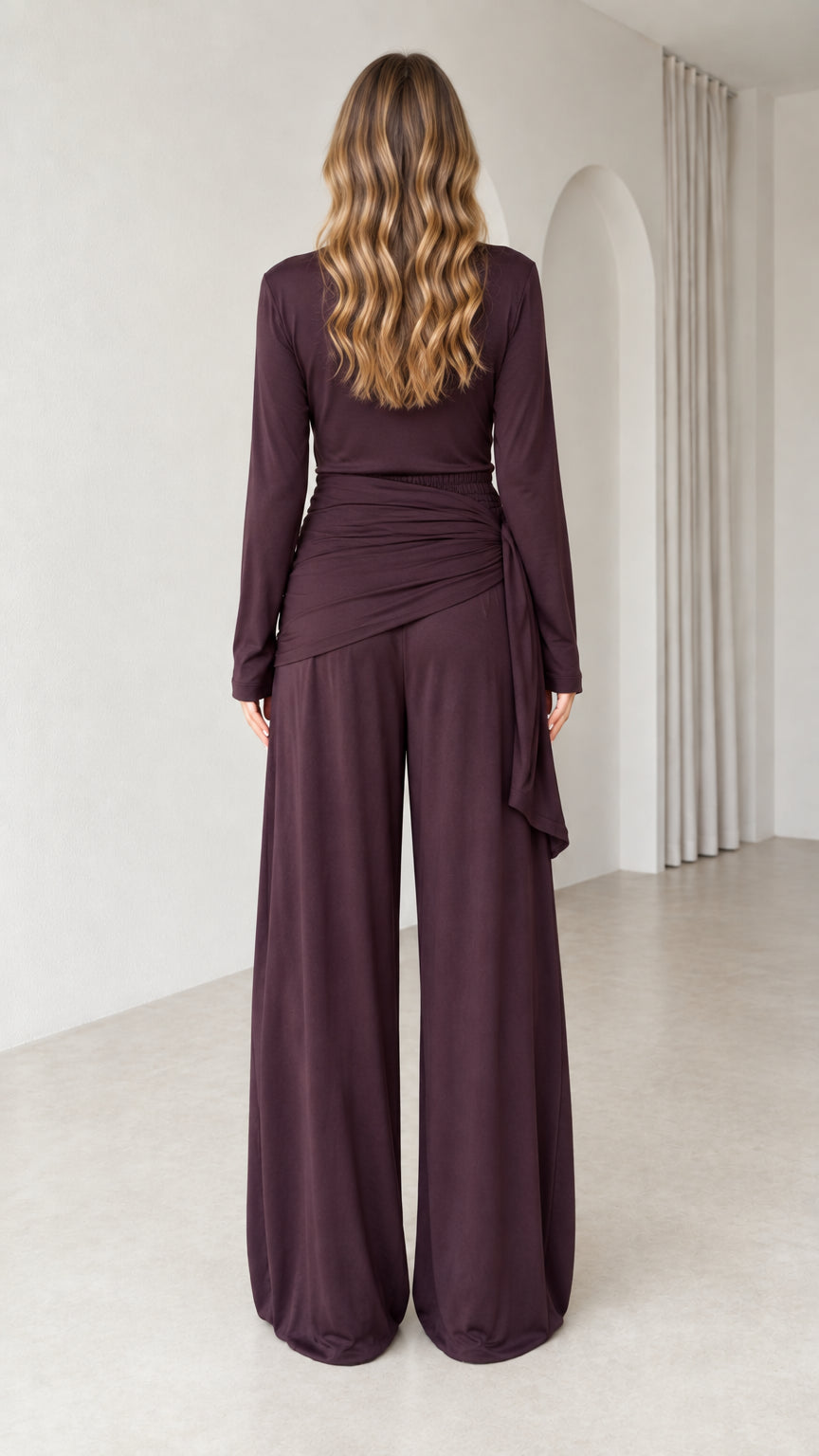 Back view of woman in plum two-piece long sleeve top and relaxed wide-leg pants