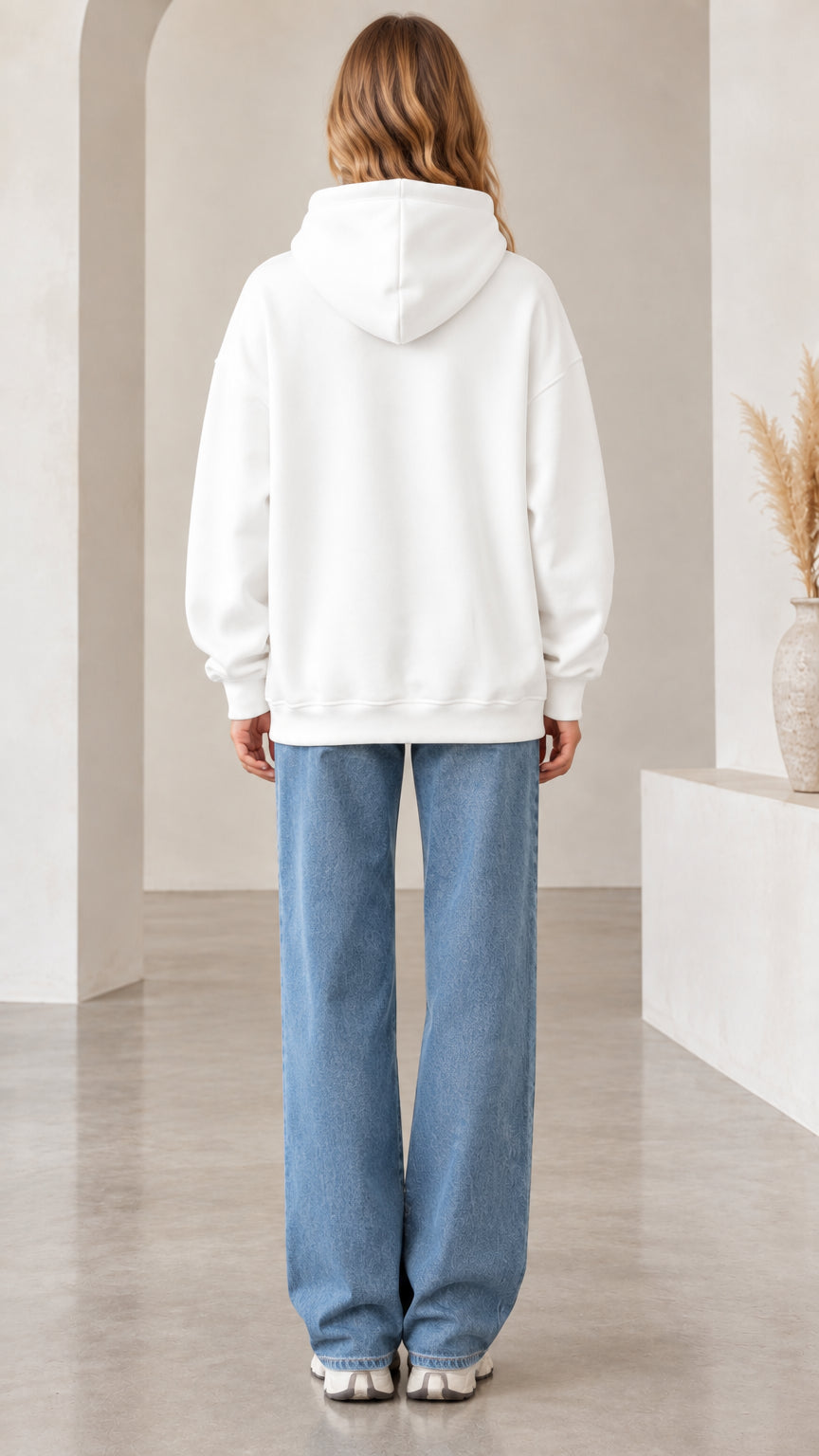 Back view of woman wearing white pullover hoodie with hood up
