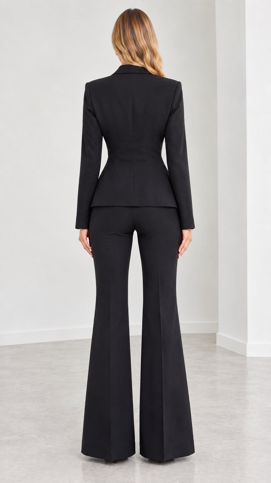 Back view of model in structured black blazer and flared dress pants