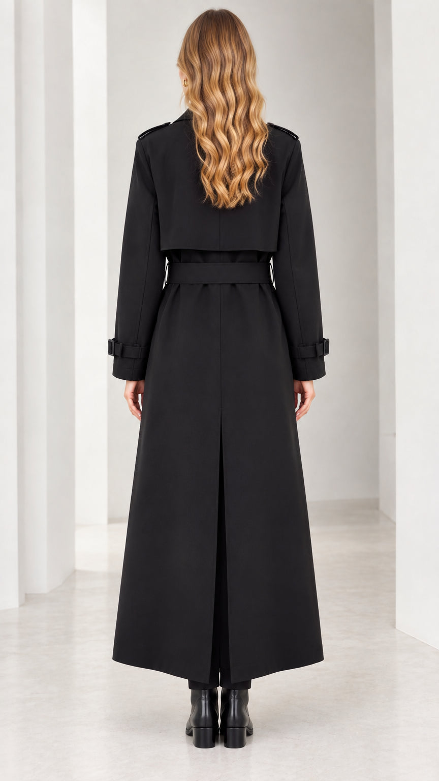 Back view of woman in black maxi trench coat showing belted waist and back vent