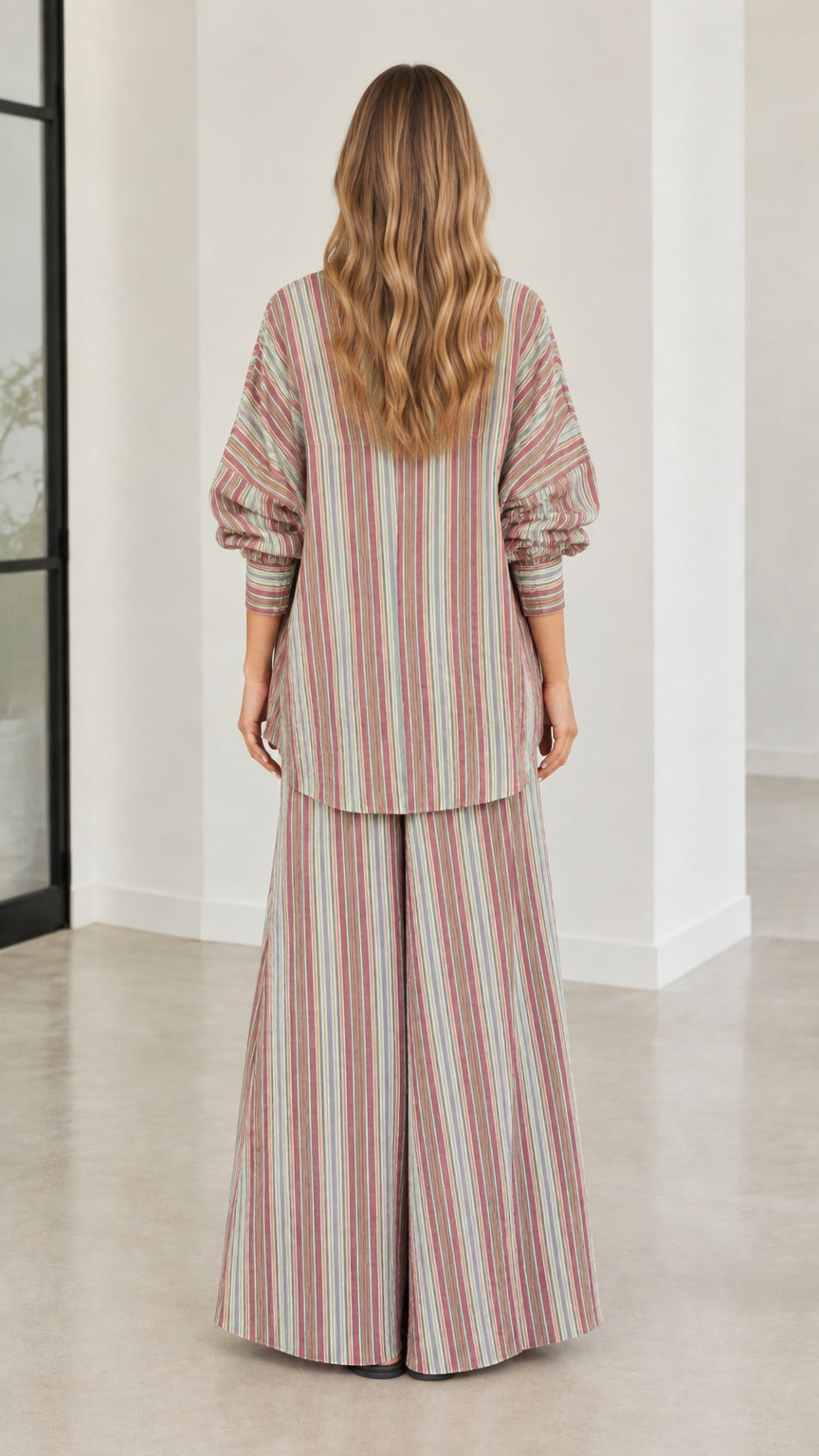 Back view of model wearing relaxed fit striped button-down tunic and wide-leg pants