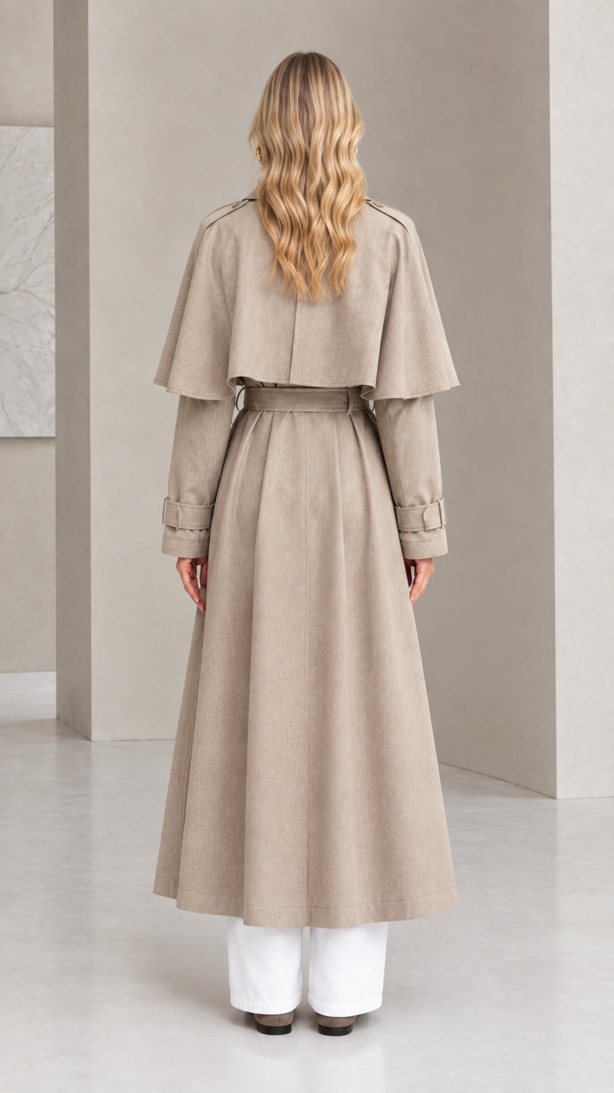 Back view of taupe maxi trench coat highlighting capelet back flap and belted waist