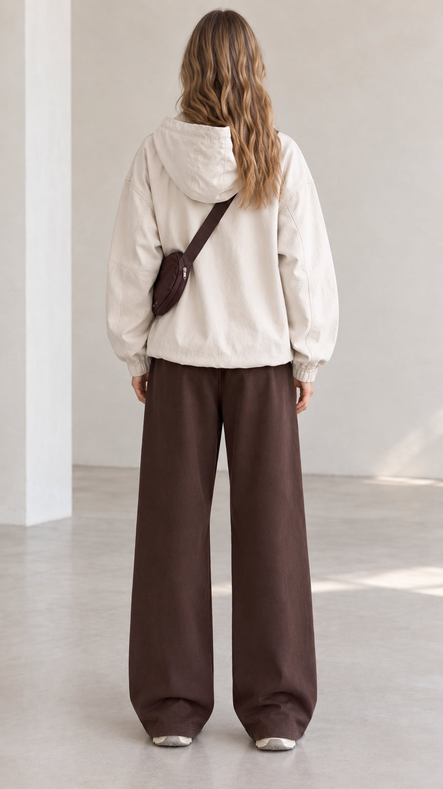 Back view of model wearing beige lightweight hooded pullover jacket