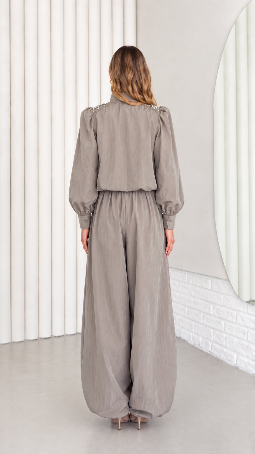 Back view of model wearing taupe grey relaxed-fit long sleeve jumpsuit