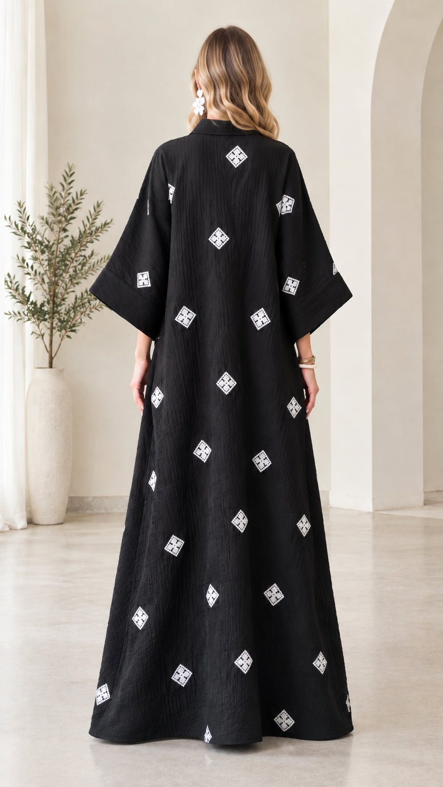 Back view of model wearing loose black embroidered crinkle maxi kaftan