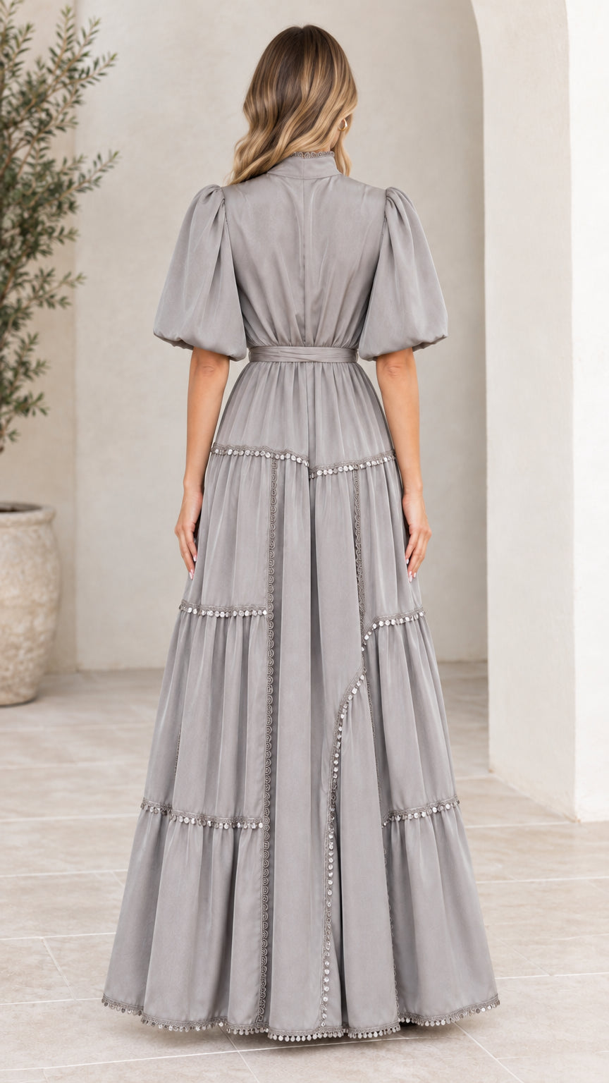Back view of woman wearing elegant grey tiered maxi dress with belted waist