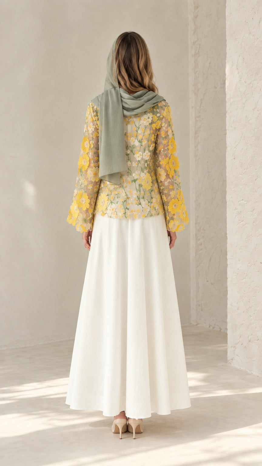 Back view of model wearing flowing white maxi dress with sheer floral lace jacket