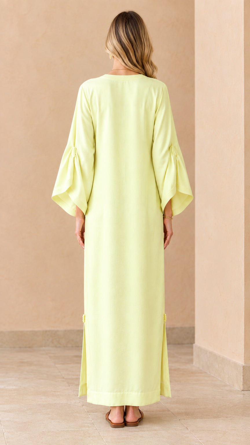 Back view of woman wearing pale yellow maxi length kaftan dress