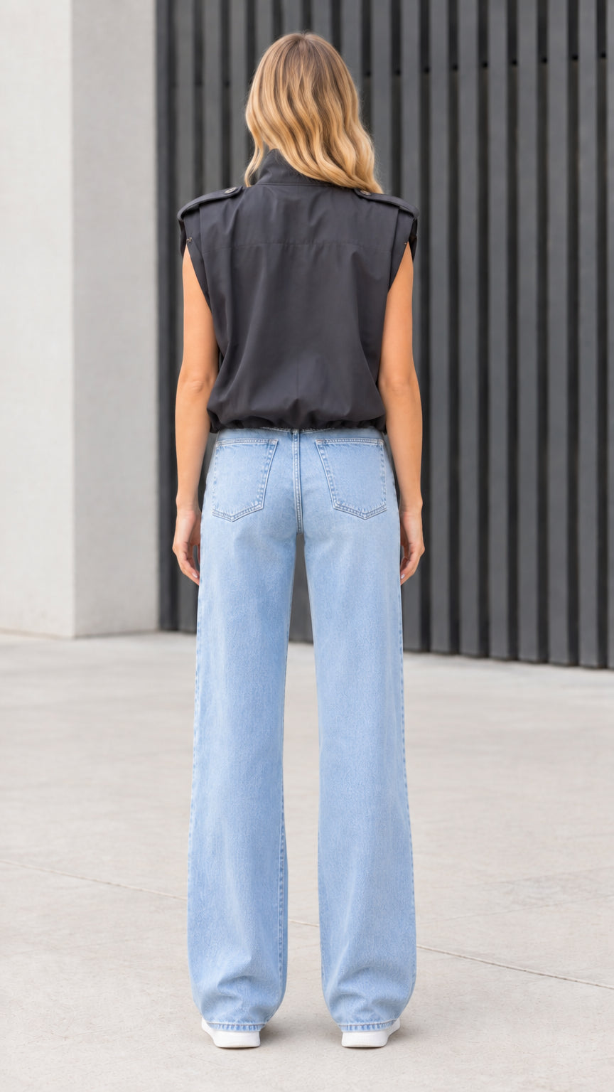 Back view of model wearing black high-neck sleeveless vest with elastic hem