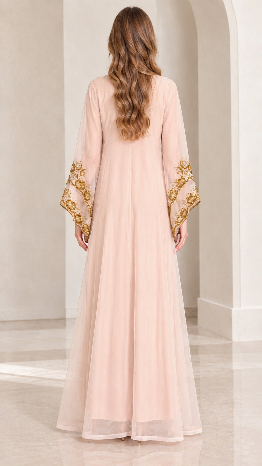 Back view of woman in flowing blush pink floor-length kaftan dress