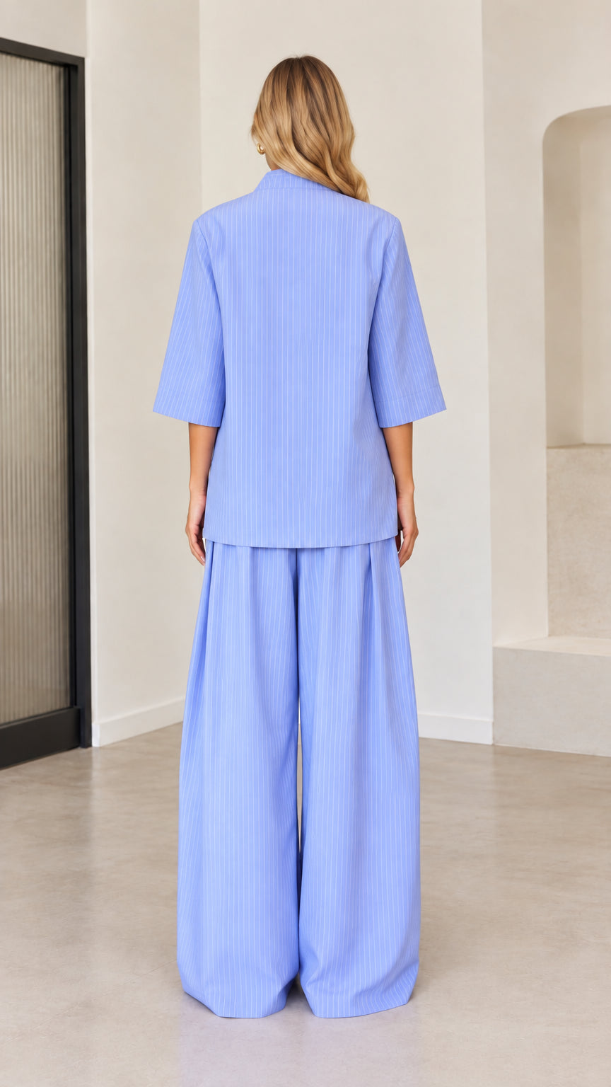Back view of women's light blue pinstripe elbow sleeve top and relaxed wide leg trousers