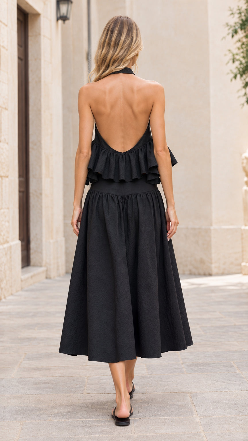 Back view of model showcasing the open back halter ruffle top and black midi skirt