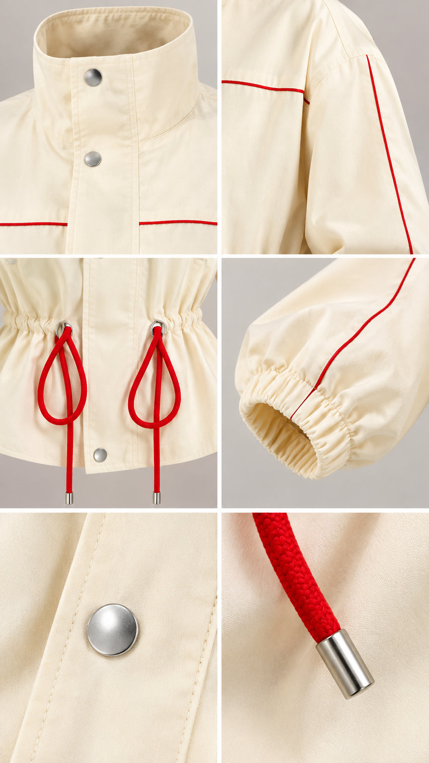 Close-up details of collar, snap buttons, red drawstring cords, and elastic cuff on cream jacket