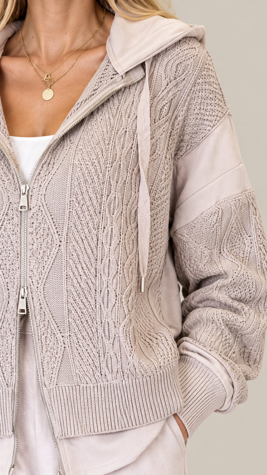 Close-up detail of Oatmeal cable-knit pattern, metal front zipper, and drawstring hood