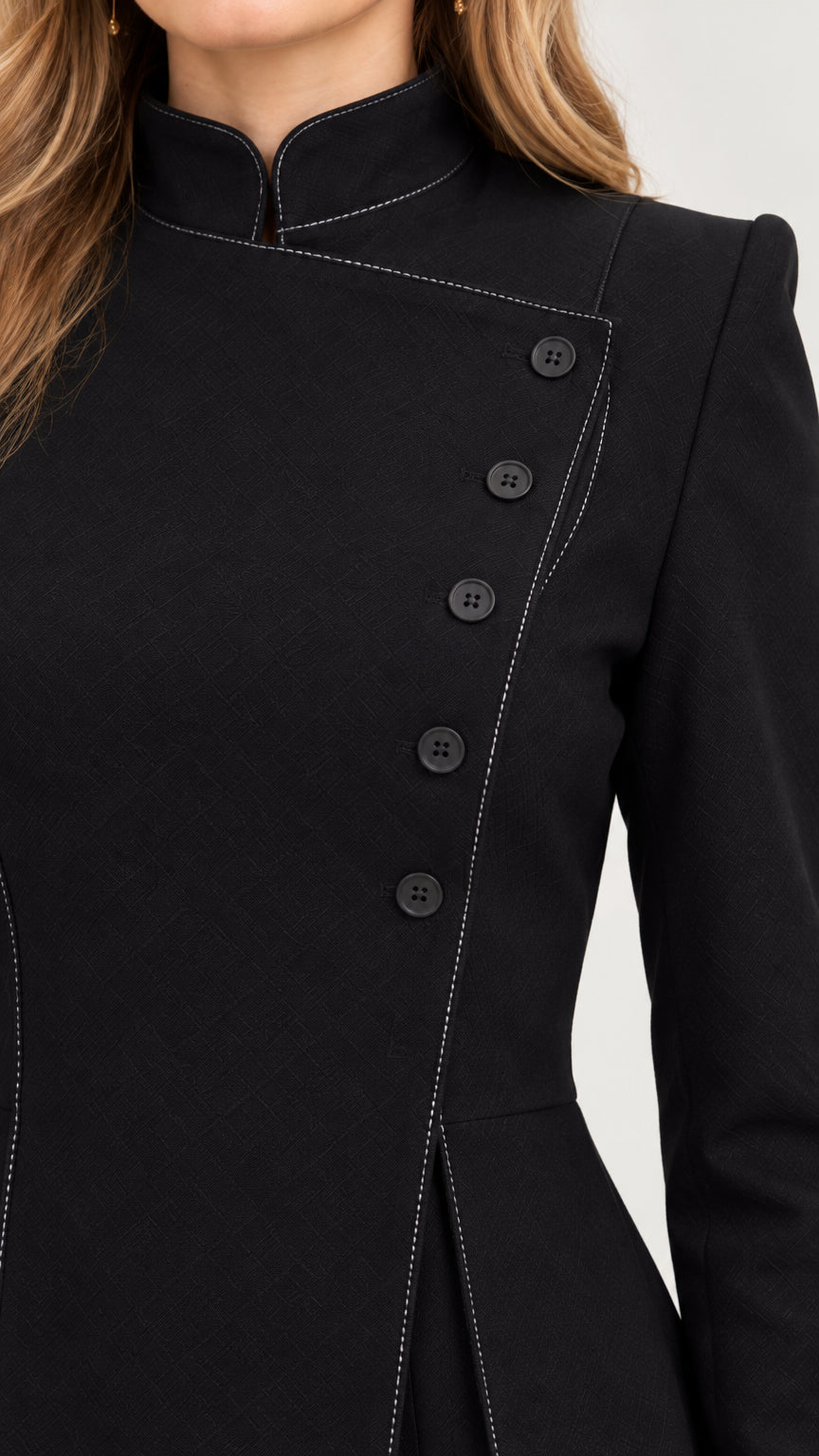 Close-up detail of black blazer with asymmetric button closure and contrast topstitching