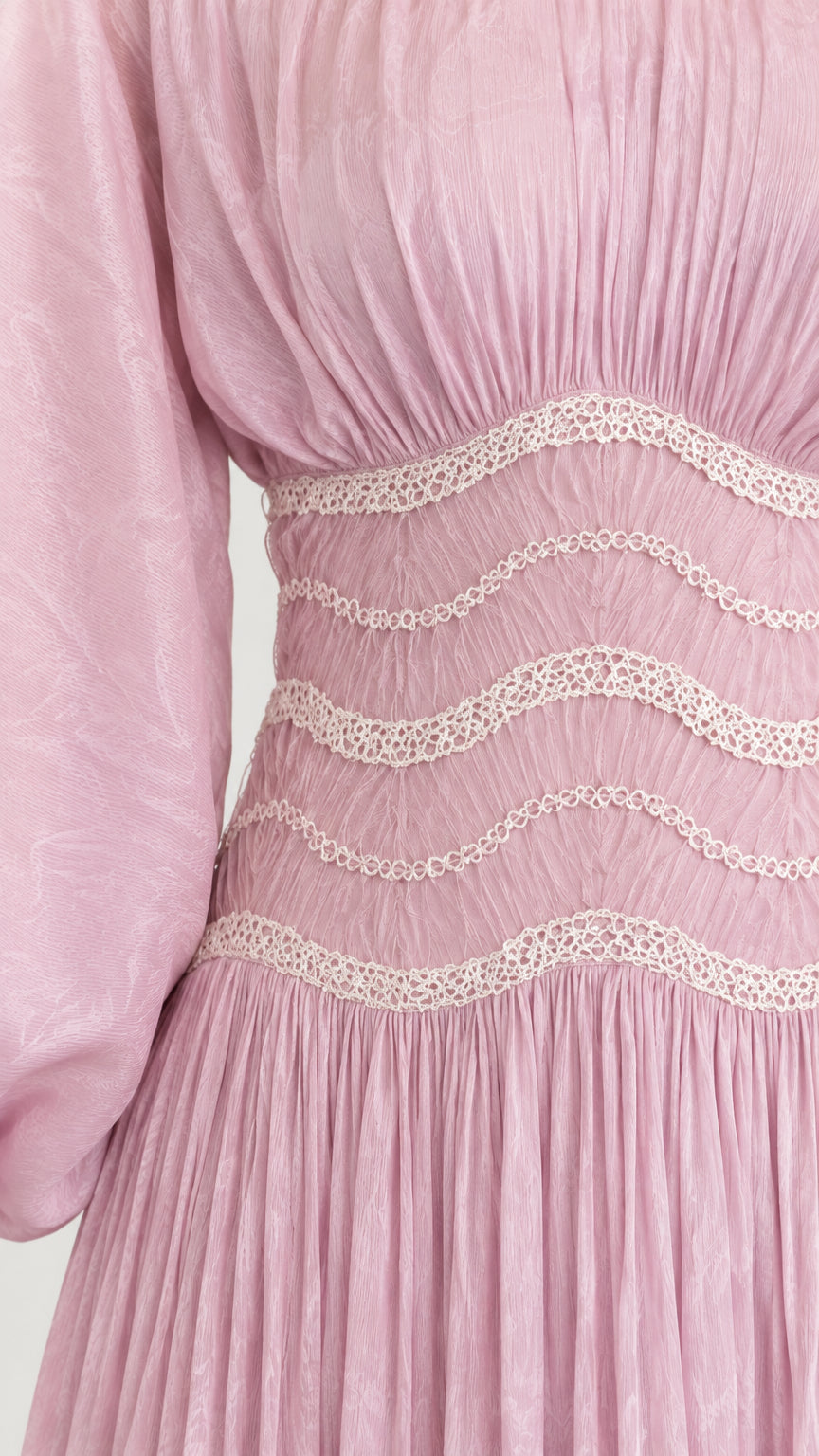 Close-up detail of wavy embroidered waistband and pleated fabric