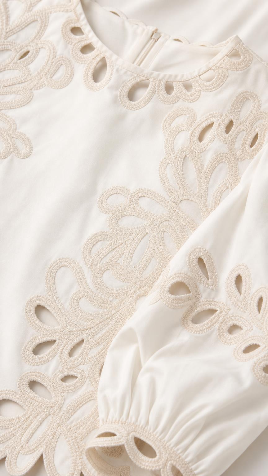 Close-up detail of white embroidery and cutout fabric