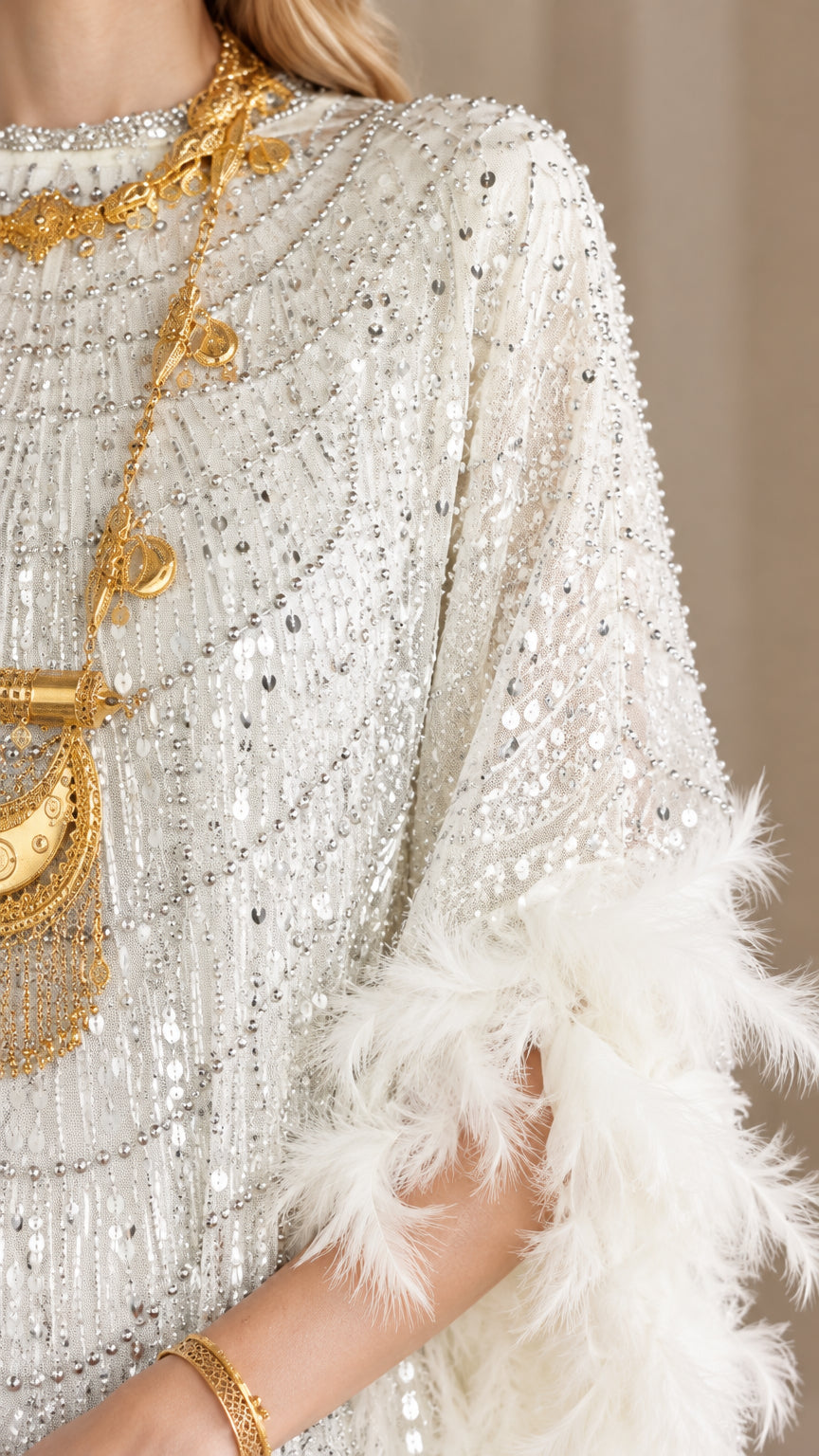 Close-up detail of white sequin fabric embellishments and feather sleeve trim