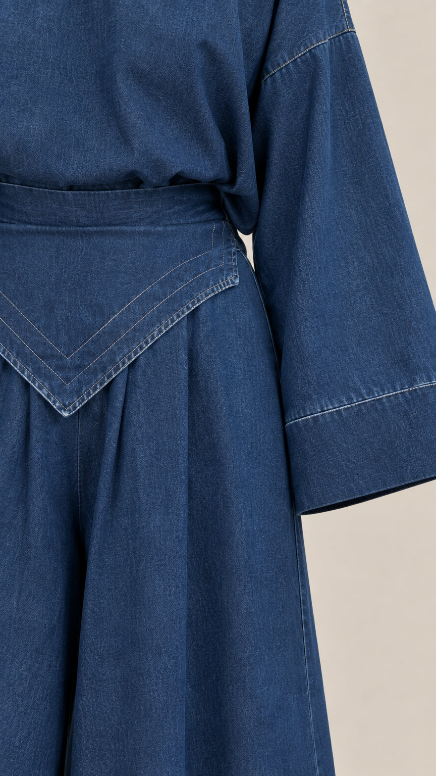 Close-up of V-shaped waistband and wide sleeve hem on denim blue set