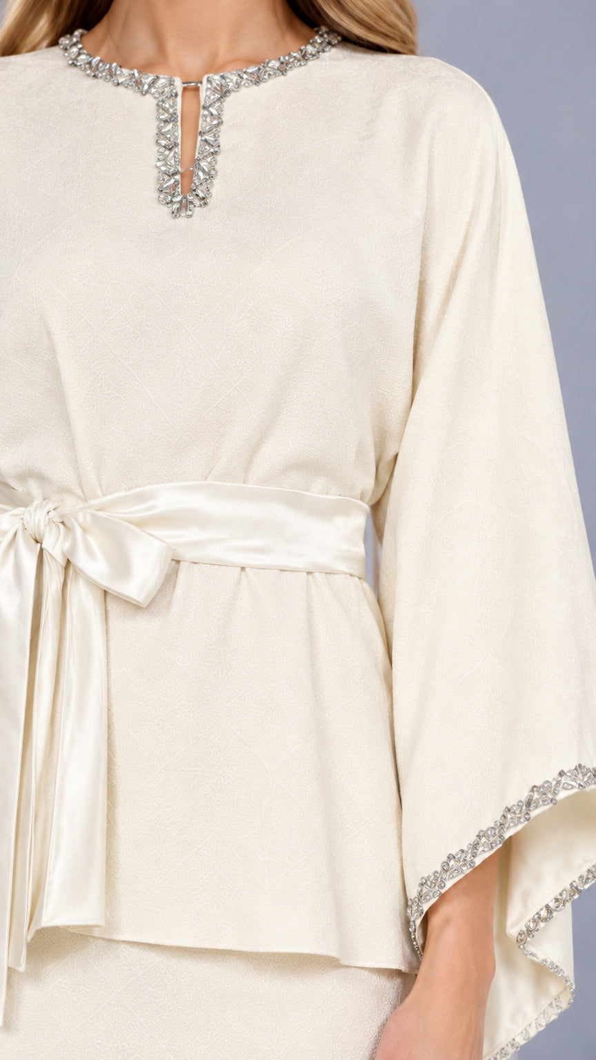 Close-up detail of rhinestone neckline, sash tie belt, and cuff embellishment