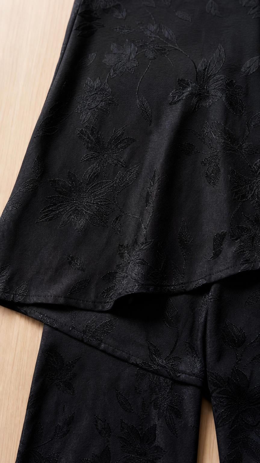 Close-up of black jacquard fabric texture and asymmetrical hem