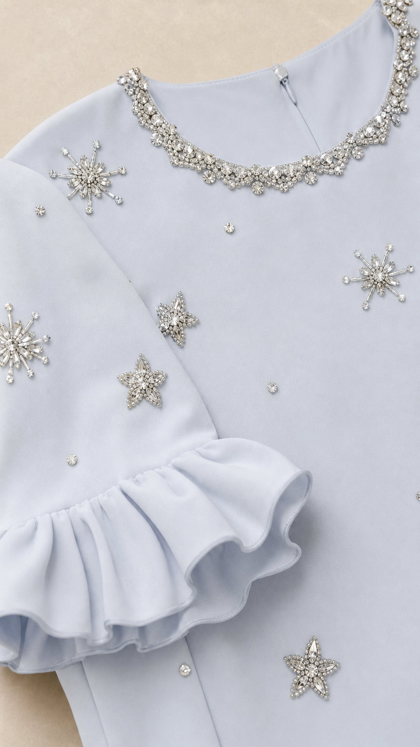 Close-up of crystal neckline and star embellishments on light blue dress