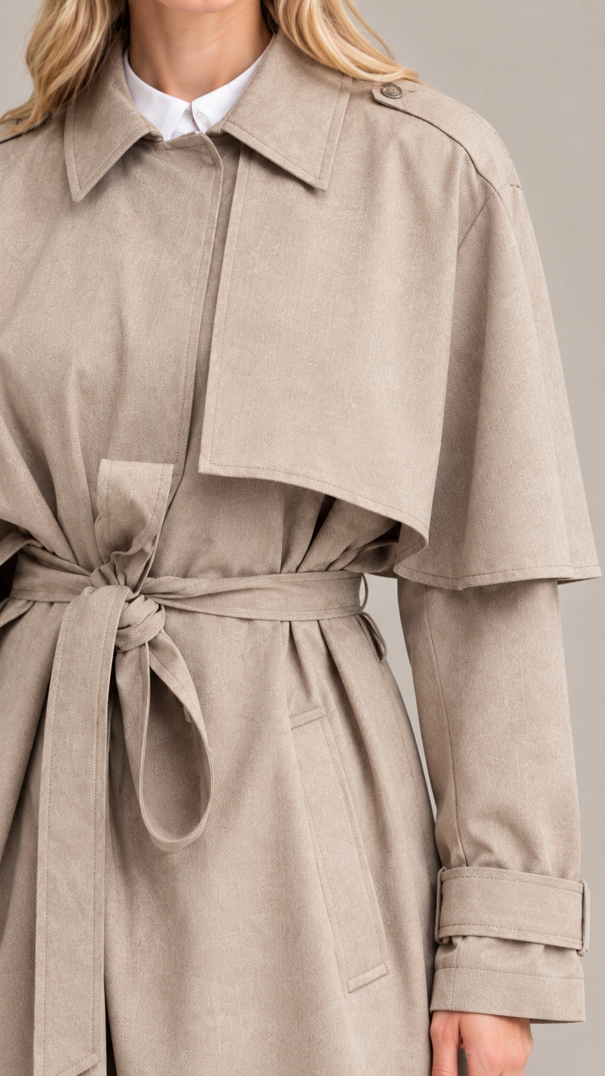 Close-up detail of collar, storm flap cape, and belted waist on taupe trench coat