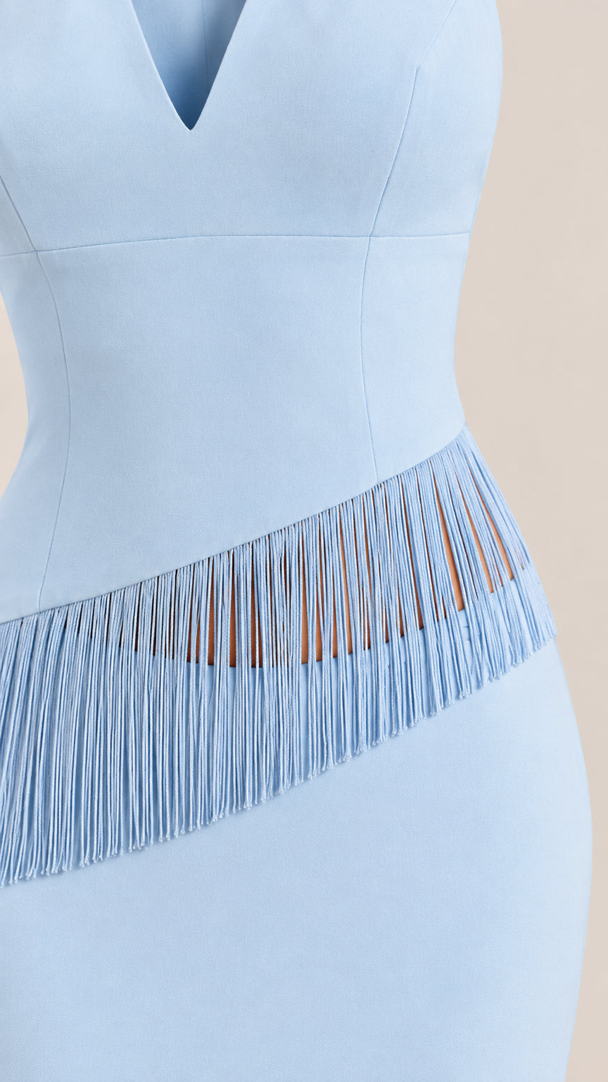 Close-up of waistline showing diagonal fringe trim detail on light blue dress