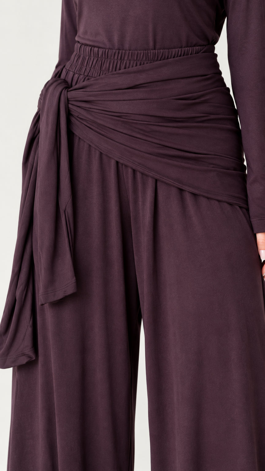 Close-up detail of the draped tie-waist sash and elastic waistband on wide-leg trousers