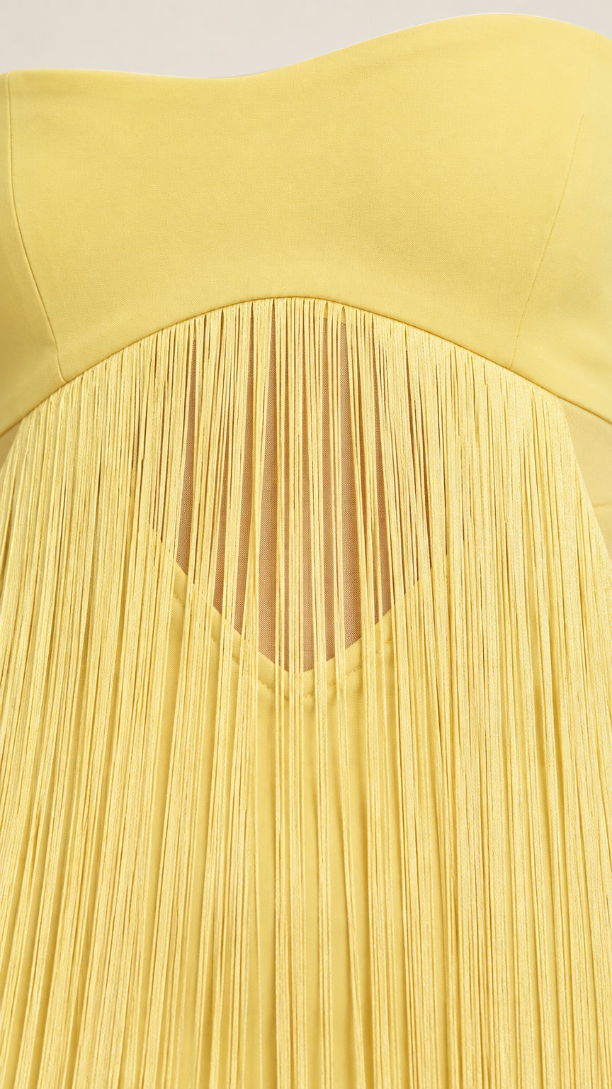 Close-up detail of yellow fringe and under-bust cutout design