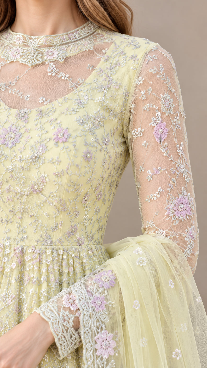 Close-up detail of sheer illusion neckline and pastel floral embroidery on pale yellow gown