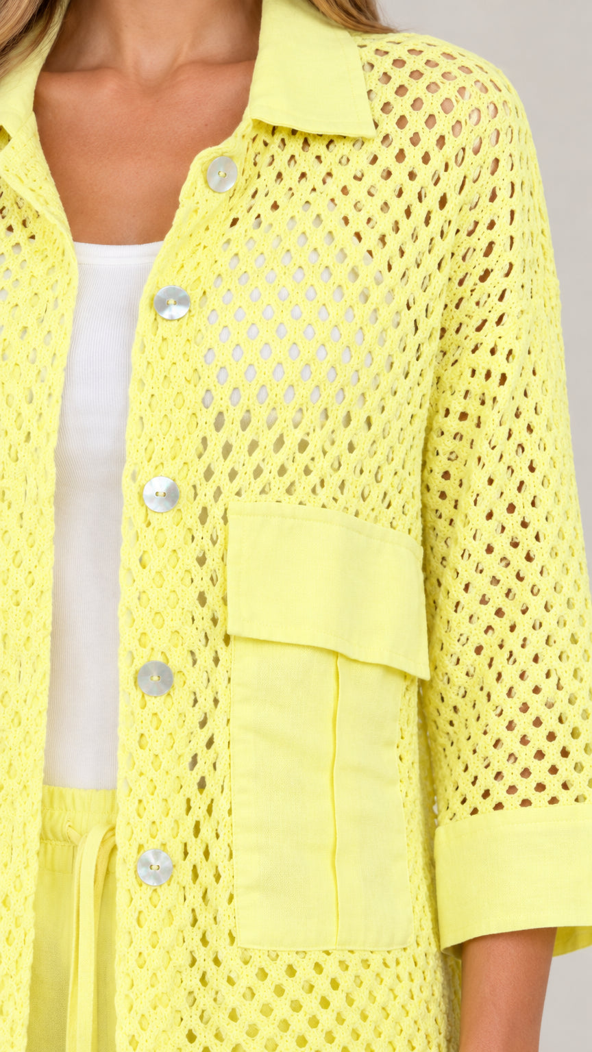 Close-up detail of light yellow open knit fabric, collar, buttons, and pocket