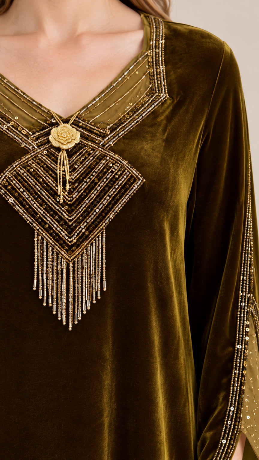 Close-up detail of metallic embroidery, gold flower medallion, and beaded tassel fringe on velvet dress