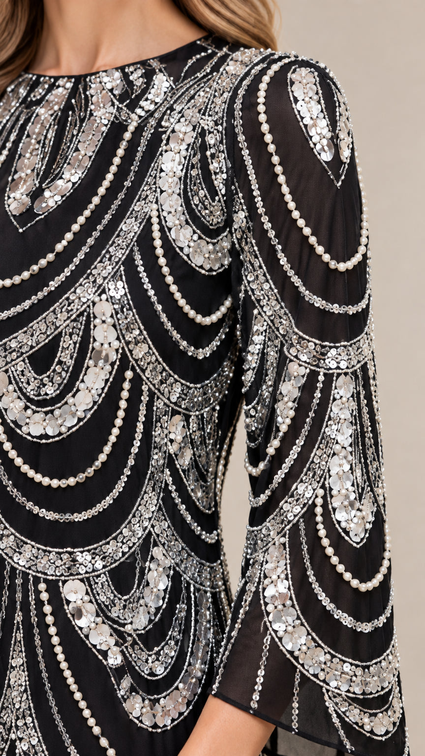 Close-up detail of silver sequin and beaded scallop pattern on sheer black fabric